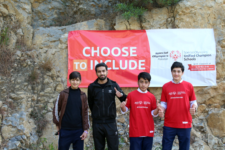 Students with and without intellectual disabilities posing in front of a Special Olympics Pakistan banner that encourages inclusion